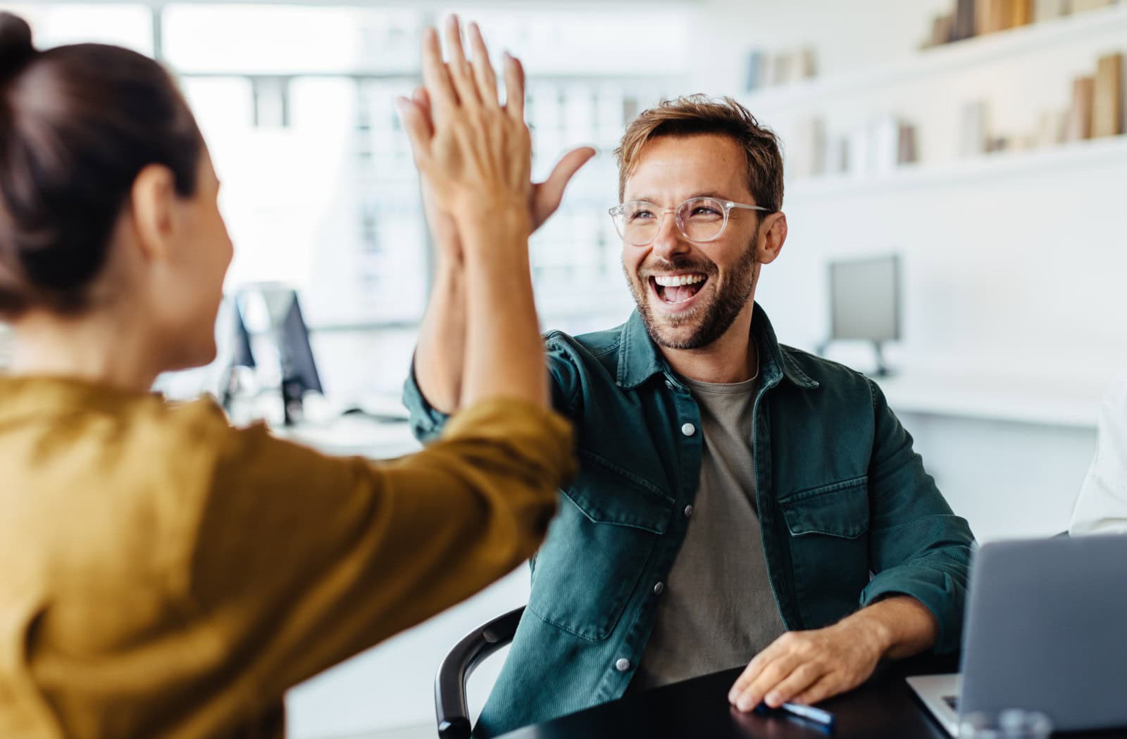 Kolegové si dávají high five v moderní kanceláři - úspěšné spolupráce díky spolehlivému webhostingu a profesionálním doplňkovým službám od Active24