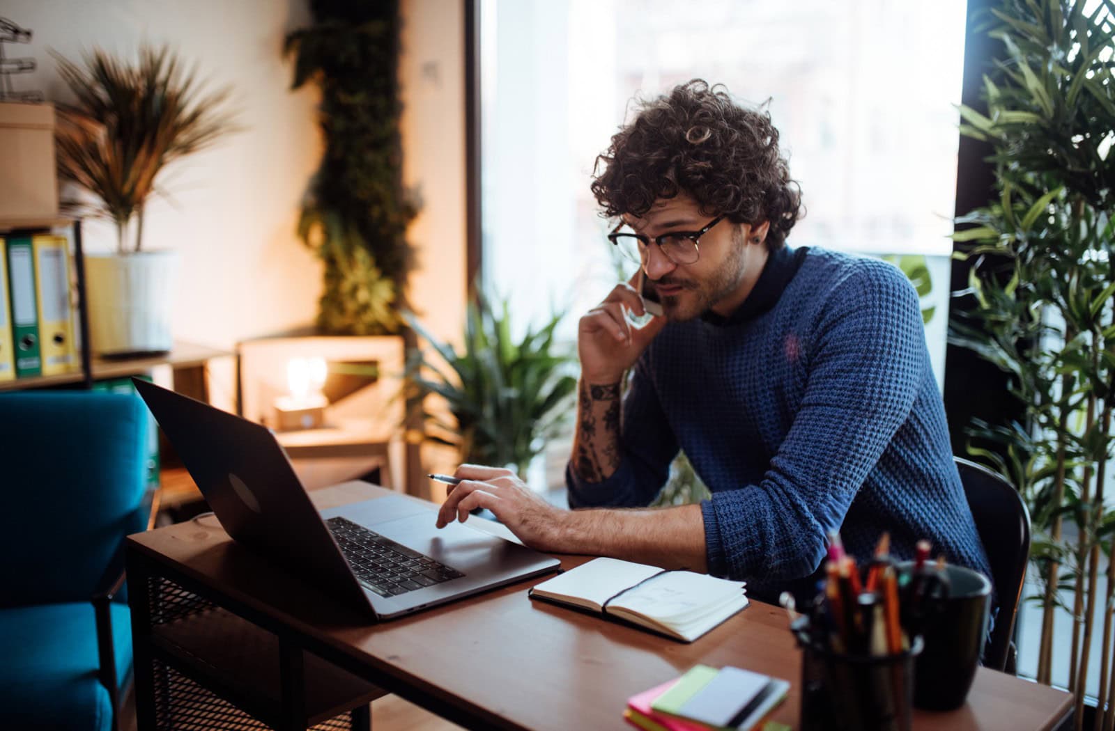 Podnikatel pracuje na notebooku a telefonuje v moderní kanceláři – profesionální firemní e-mail a hosting od Active 24 pro efektivní online komunikaci a správu podnikání.