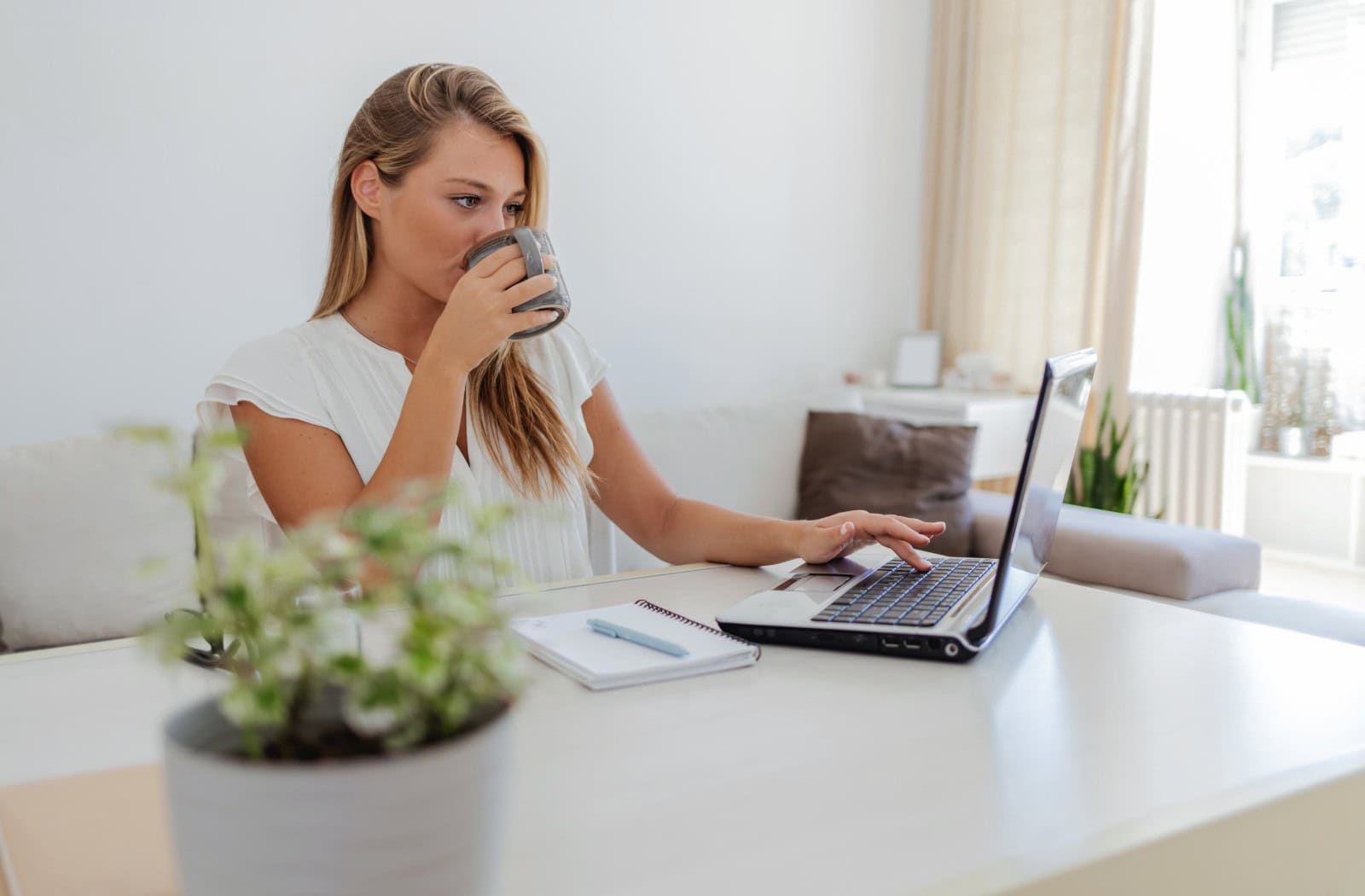 Žena pracující z domova na notebooku a s kávou v ruce - snadná správa vlastního webu díky intuitivnímu webovému editoru a webhostingu od Active24
